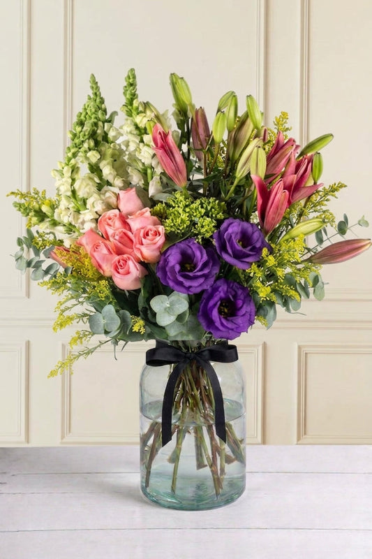 Arreglo 9 Rosas Claritas, 6 Lilys Rosas, 3 Lisianthus, Perrito Blanco con Solidago y Eucalipto - En Florero | MJO
